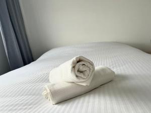 een opgerolde witte handdoek zittend op een bed bij Mickey House à 10 min Disneyland in Montévrain