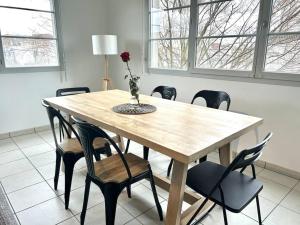 een houten tafel met stoelen en een vaas met een bloem erop bij Mickey House à 10 min Disneyland in Montévrain