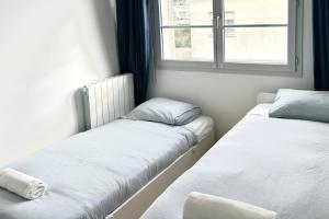 two beds in a room with a window at Mickey House à 10 min Disneyland in Montévrain