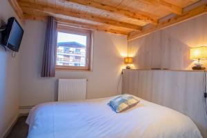 a bedroom with a white bed and a window at Spacious apartment with terrace - Alpe d'Huez - Welkeys in LʼHuez