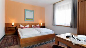 a bedroom with a bed and a desk and a window at Hotel Restaurant Onkel-Otto in Pommern