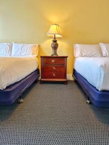 Cette chambre comprend 2 lits et une lampe sur une commode. dans l'établissement Winthrop Arms Hotel Restaurant Logan Airport, à Winthrop