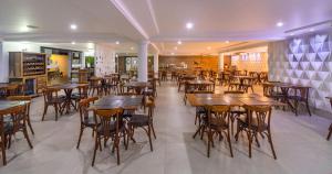 a restaurant with wooden tables and chairs at Transoceanico Praia Hotel in Porto Seguro