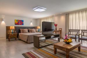 uma sala de estar com uma cama e uma televisão em Transoceanico Praia Hotel em Porto Seguro