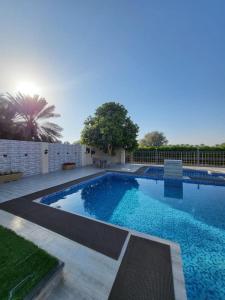 una gran piscina de agua azul en un patio en Al Khamail Land for Greenhostel en Al Wāşil