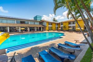 uma piscina com cadeiras e palmeiras em frente a um hotel em Transoceanico Praia Hotel em Porto Seguro