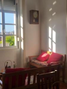 a room with a couch with red pillows and a window at Cubicullum in Vila Nova de Gaia