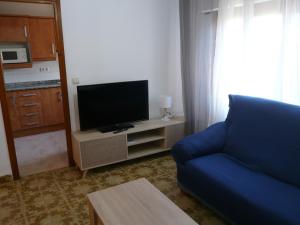a living room with a blue couch and a tv at CASA INOCENCIA in Alcossebre