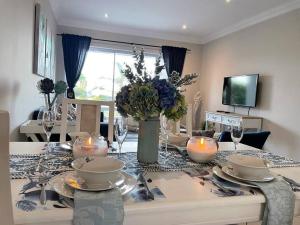uma mesa de jantar com velas e um vaso de flores em Alnily Sea View Luxury Self Catering Accommodation em Jeffreys Bay