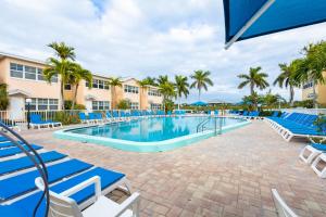 a swimming pool with blue chairs and palm trees at Premier 2BD Waterfront Condo Barefoot Beach Resort in Clearwater Beach