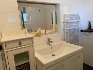 a white bathroom with a sink and a mirror at Charming Villach Hideaway - 1BR in Villach