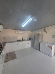 a large kitchen with a refrigerator and white cabinets at Al Khamail Land for Greenhostel in Al Wāşil