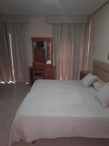1 dormitorio con 1 cama blanca grande y espejo en Hotel Roma, en San Fernando