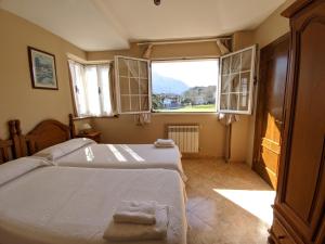 a bedroom with two beds and a large window at Apartamentos Bricia in Posada de Llanes