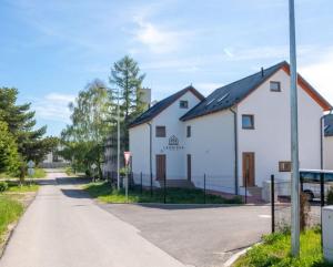 a white building with a black roof on a street at Chata Lesnička in Nová Lesná