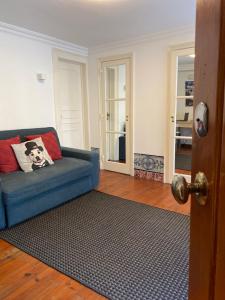 Cozy Estrela Apartment في لشبونة: غرفة معيشة مع أريكة زرقاء وسجادة