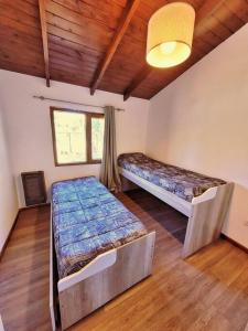 ein Schlafzimmer mit zwei Betten in einem Zimmer mit Holzdecken in der Unterkunft Casa en San Carlos de Bariloche in San Carlos de Bariloche