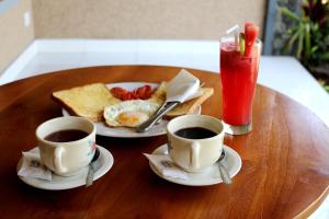 a wooden table with two cups of coffee and toast at Magus Homestay in Pemuteran