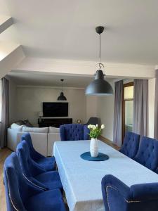 a living room with a table and blue chairs at Apartament DeLux in Pasłęk