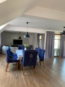 a dining room with blue chairs and a table at Apartament DeLux in Pasłęk