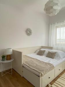 a white bedroom with a bed and a lamp at Apartament DeLux in Pasłęk