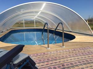 a swimming pool in a dome with a metal roof at Le Bois Gautier in Savigny-le-Vieux
