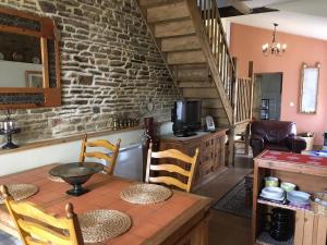 ein Wohnzimmer mit einer Steinmauer sowie einem Tisch und Stühlen in der Unterkunft Le Bois Gautier in Savigny-le-Vieux