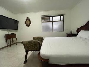 1 dormitorio con 1 cama, TV y silla en Quiet apartment in Laureles, en Medellín