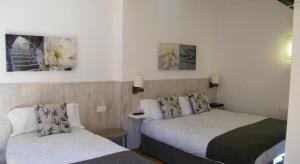 Habitación de hotel con 2 camas y pinturas en la pared en HOTEL LAMOGA, en Llavorsí