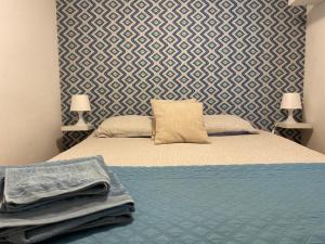 Cozy Estrela Apartment في لشبونة: غرفة نوم بسرير وبطانية زرقاء وجدار