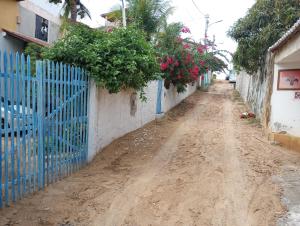 an empty dirt road next to a blue fence at Chalé Flor do Ser in Canoa Quebrada