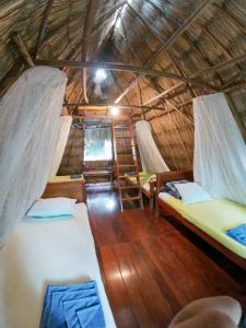 a room with two beds in a straw hut at Posada del Cerro in El Remate
