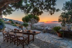 einen Tisch und Stühle auf einer Steinterrasse mit Sonnenuntergang in der Unterkunft Alma Loca Syros in Ermoupoli