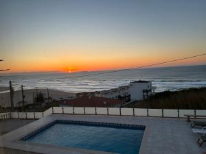 puesta de sol sobre el océano con piscina en Mãe Home Foz, en Foz do Arelho
