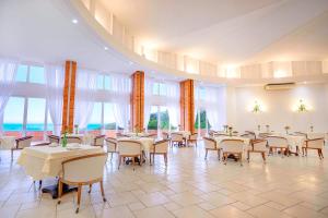 a dining room with tables and chairs and windows at Samba Laguna Tourist Hotel in Laguna