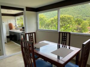 una sala da pranzo con tavolo, sedie e finestra di Cantinho na natureza perto das praias a Niterói