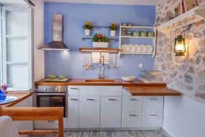 a kitchen with a sink and a blue wall at Braxos A beautiful rocky place in Hydra