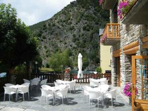 a group of white tables and chairs on a patio at HOTEL LAMOGA in Llavorsí