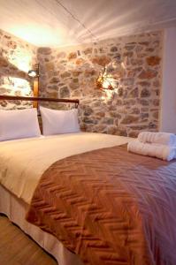 a bedroom with a large bed with a stone wall at Braxos A beautiful rocky place in Hydra
