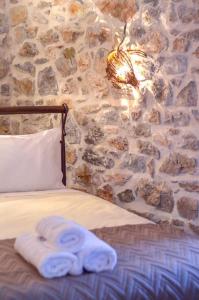 a bedroom with a stone wall and a bed with towels at Braxos A beautiful rocky place in Hydra