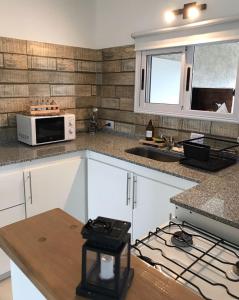 a kitchen with white cabinets and a sink and a microwave at La Pasionaria casa de sierras in Santa Rosa de Calamuchita