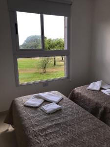 two beds in a room with a window at La Pasionaria casa de sierras in Santa Rosa de Calamuchita