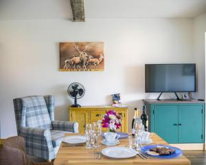 a dining room with a table and a tv at The Tack Room at Castle Chase Ayston 
