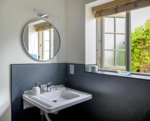 ein Badezimmer mit einem weißen Waschbecken und einem Spiegel in der Unterkunft The Tack Room at Castle Chase Ayston 