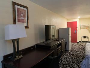 um quarto com uma secretária, uma televisão e um frigorífico em FairBridge Inn Express Hiawatha em Hiawatha