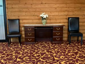 due sedie e una scrivania con un vaso di fiori di FairBridge Inn Express Hiawatha a Hiawatha