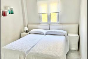 een wit bed in een witte slaapkamer met een raam bij MI CAPRICHO BEACHFRONT- P301 Apartment with sea view in Mijas Costa