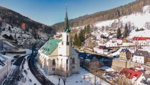 Eine Kirche mit einem Kirchturm in einer Stadt im Schnee in der Unterkunft Apartmán Albreit in Jáchymov