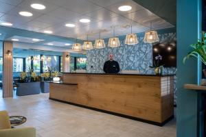 a man standing behind a counter in a lobby at Ohalo Manor Hotel in Kinneret