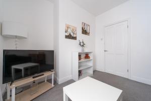 a white living room with a flat screen tv at Homely 1BD Apt with Free Street Parking in Scunthorpe